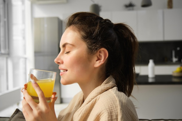 Kostenloses Foto nahaufnahme porträt einer schönen frau, die morgens mit vergnügen ein glas orangensaft trinkt