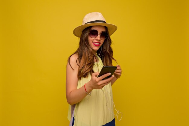 Nahaufnahme Porträt eines glücklichen Mädchens lächelt über gelbem Boden Braunhaarige Frau im sommerlichen gelben Kleid und Hut lächelt breit mit ihren Zähnen Gute Laune Konzept Freizeit
