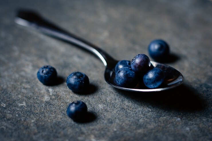Kostenlose Foto nahaufnahme schuss von frischen organischen blaubeeren silberlöffel auf holztisch