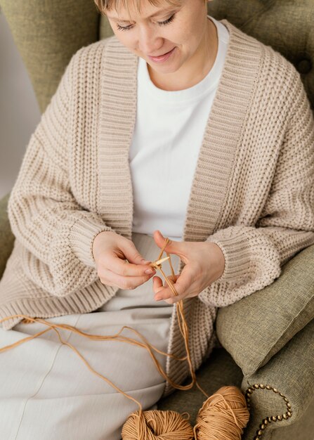 Nahaufnahme Smiley-Frau auf Sessel stricken