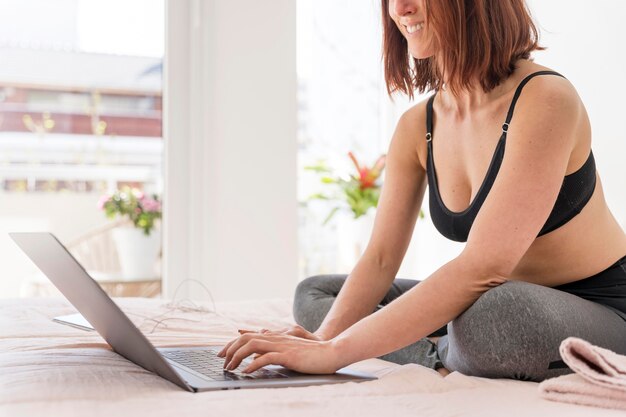 Nahaufnahme Smiley-Frau mit Laptop im Bett