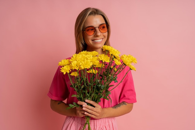 Nahaufnahme Studioportrait og Fröhliche süße blonde Frau mit Frühlingsblumen auf rosa Hintergrund