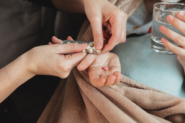 Nahaufnahme Trieb der Mutter, die Pillen für kleine Tochter gibt, die sich mit Coronavirus-Symptomen in mildem Zustand krank fühlen