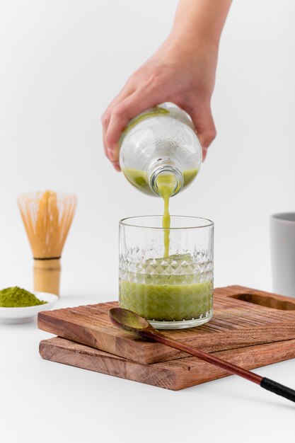 Nahaufnahme übergeben das Gießen von matcha Tee in Glas