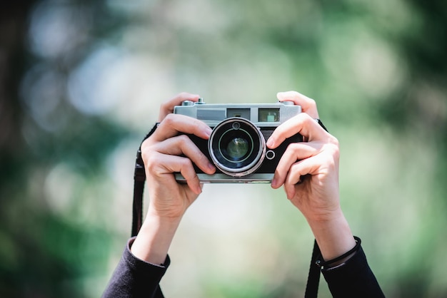 Nahaufnahme und selektiver Fokus Hände einer professionellen Fotografin, die eine Digitalkamera hält, um Schnappschüsse im Kopierraum des Naturwaldes zu machen