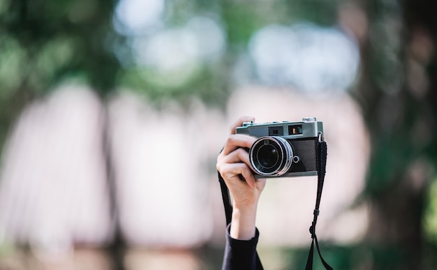 Nahaufnahme und selektiver Fokus Hände einer professionellen Fotografin, die eine Digitalkamera hält, um Schnappschüsse im Kopierraum des Naturwaldes zu machen