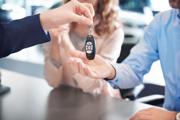 Nahaufnahme von Autoschlüsseln, die an die Hände des Kunden übergeben werden