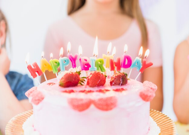 Nahaufnahme von bunten glühenden Geburtstagskerzen auf Erdbeerestückenkuchen