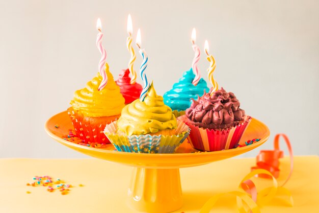 Nahaufnahme von bunten Muffins mit belichteten Kerzen auf cakestand