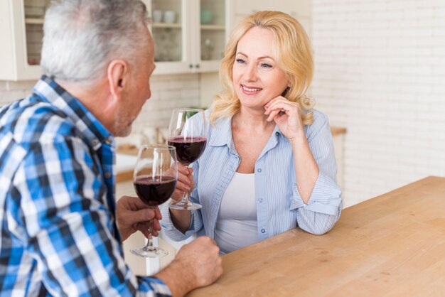 Nahaufnahme von den älteren Paaren, die den Wein in der Küche genießen