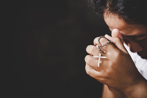 Nahaufnahme von den christlichen älteren Frauenhänden, die gekreuzigtes Kreuz beim Beten des Gottes halten.