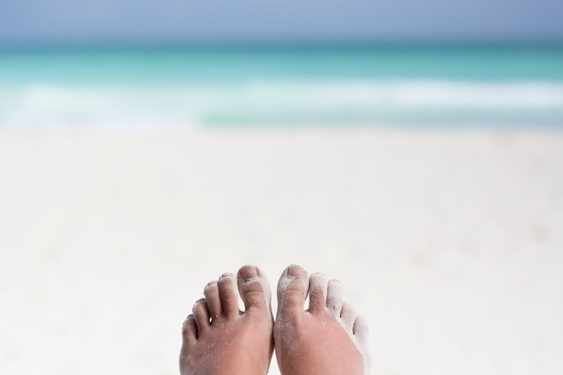 Nahaufnahme von den Füßen bedeckt im Sand am Strand