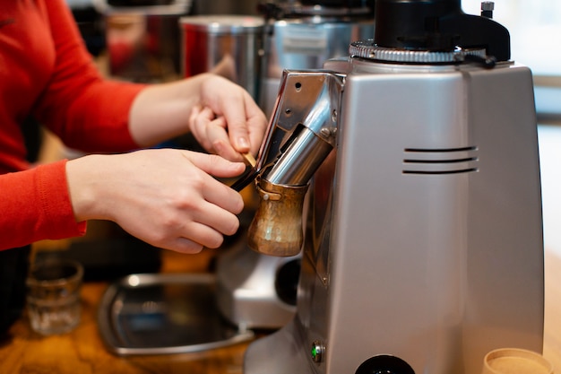 Nahaufnahme von den Händen, die an Kaffeemaschine arbeiten