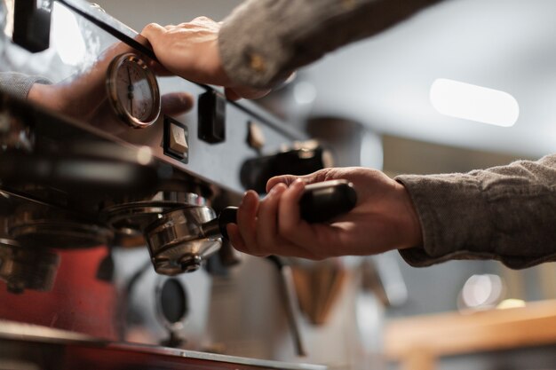 Nahaufnahme von den Händen, die an Kaffeemaschine arbeiten