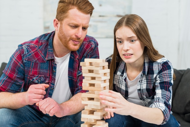 Nahaufnahme von den jungen Paaren, die den Holzklotzturm spielen