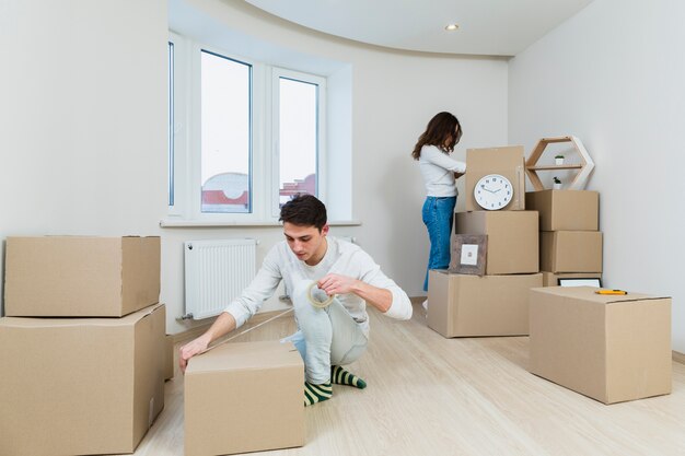 Nahaufnahme von den jungen Paaren, die zu Hause die Pappschachtel verpacken