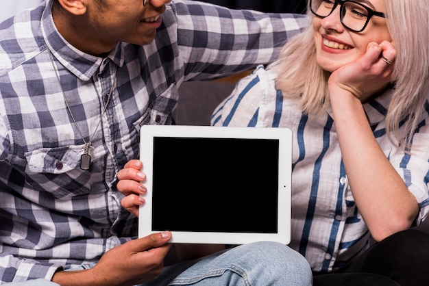 Nahaufnahme von den zwischen verschiedenen Rassen jungen Paaren, die digitale Tablette zeigen