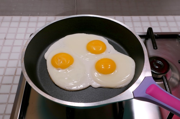 Nahaufnahme von drei eiern, die in einer pfanne gebraten werden