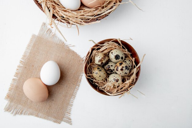 Nahaufnahme von Eiern auf Sackleinen und Schüssel von Eiern im Nest auf weißem Hintergrund mit Kopienraum