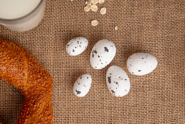 Kostenloses Foto nahaufnahme von eiern mit bagel und haferflocken auf sackleinenhintergrund mit kopienraum