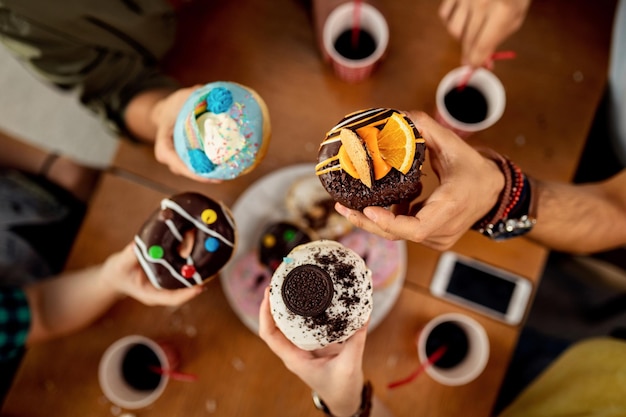 Nahaufnahme von Freunden, die bunt glasierte Donuts essen