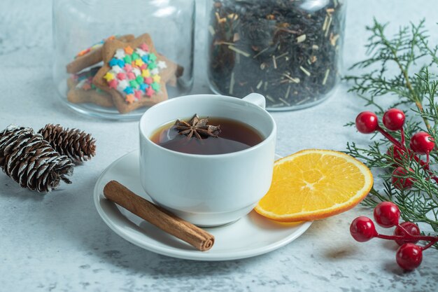 Nahaufnahme von frischem duftendem Tee mit Orangenscheibe mit Weihnachtsschmuck.
