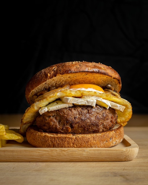 Nahaufnahme von frischen leckeren hausgemachten Rindfleischburger und Pommes Frites auf einem Holztablett