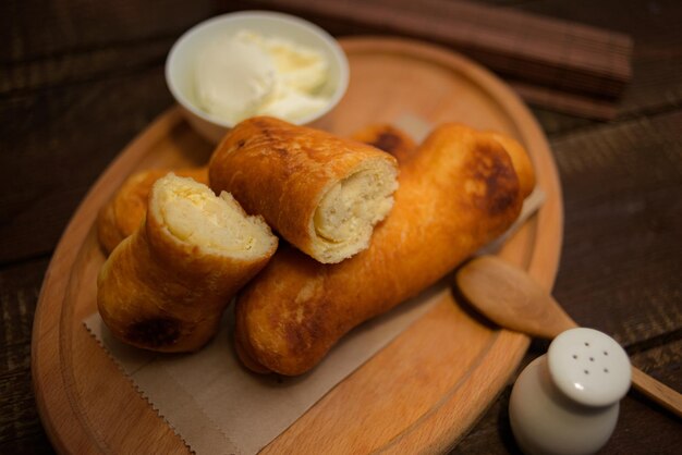 Nahaufnahme von gebratenen Eierbrötchen mit einer kleinen Schüssel Dip-Creme auf einem Holzbrett