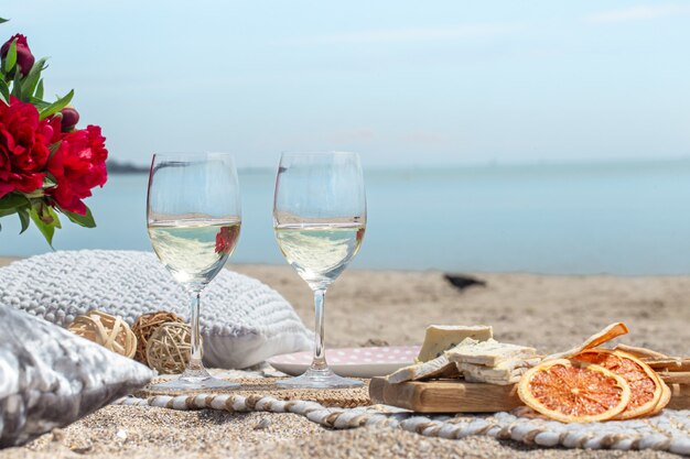 Nahaufnahme von Gläsern Champagner und Snacks an der Küste. Urlaubs- und Romantikkonzept.
