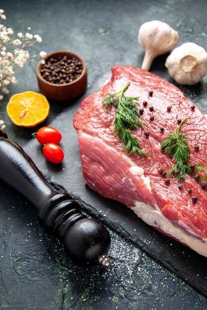 Nahaufnahme von Grün auf frischem rotem rohem Fleisch auf Schneidebrett und Pfeffer Zitrone schwarze Hammerblume auf grün-schwarzem Mischfarbhintergrund