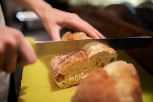 Nahaufnahme von Hand, die Brot schneidet