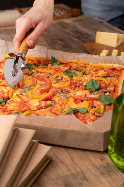 Nahaufnahme von Hand schneiden Pizza mit Werkzeug