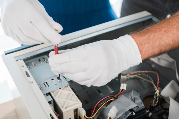Nahaufnahme von Handschuhen einer männlichen Technikerhand, die Computer reparieren