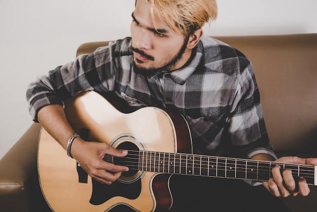 Nahaufnahme von Hipster Bart Mann Hand Gitarre spielen.