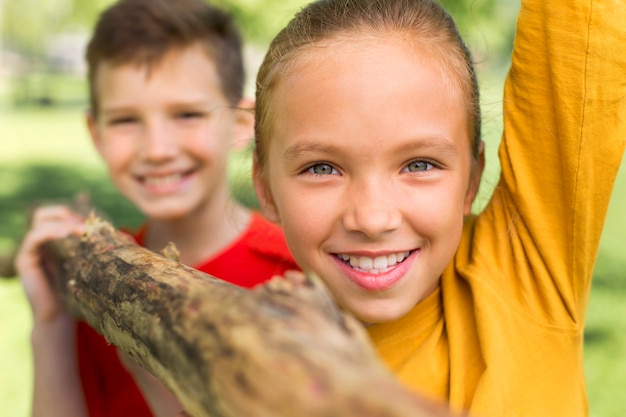 Kostenloses Foto nahaufnahme von kindern, die als team baumstamm tragen