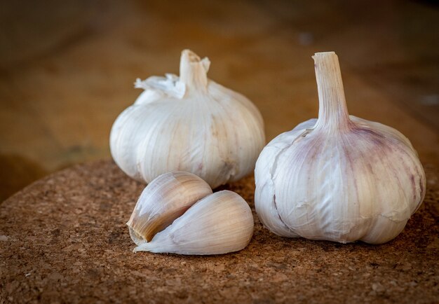 Nahaufnahme von Knoblauchknolle und Nelken auf einem runden Korkbrett