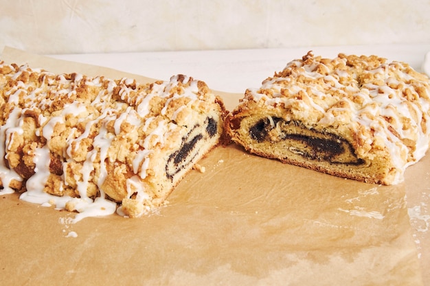 Nahaufnahme von köstlichem Mohnkuchen mit weißer Zuckerglasur auf einem weißen Tisch