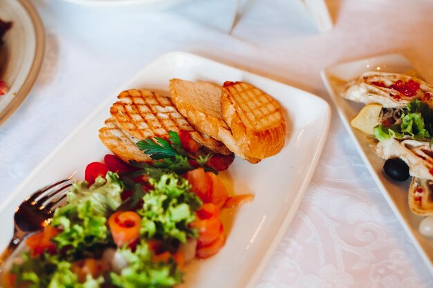 Nahaufnahme von köstlichen Fleischbällchen und Fischbrötchen, die auf rechteckigen Bällen mit Stöcken für Snacks serviert werden Auswahl an Speisen auf Geburtstagsfeier oder Hochzeitsfeier