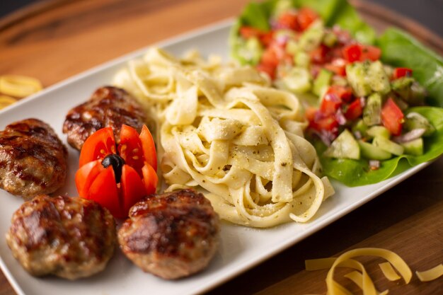 Nahaufnahme von köstlichen Nudeln, serviert mit Fleischbällchen und einem gesunden Salat