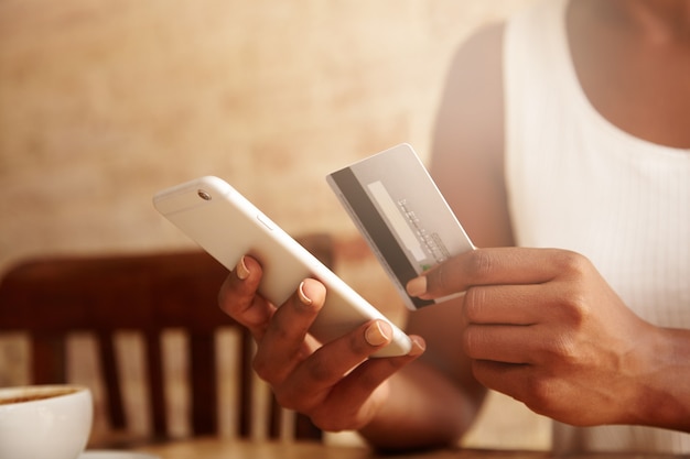 Nahaufnahme von Kreditkarte und Smartphone in den Händen der Frau