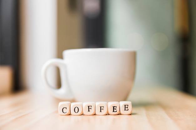 Nahaufnahme von kubikklötzen eines kaffees mit tasse kaffee auf holzoberfläche