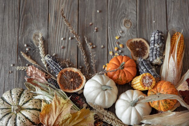 Nahaufnahme von Kürbis, Mais und Herbstlaub auf einem hölzernen Hintergrund, Ansicht von oben.