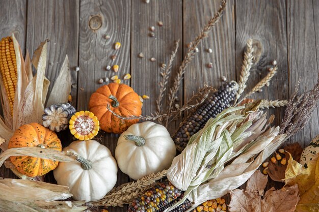 Nahaufnahme von Kürbis, Mais und Herbstlaub auf einem hölzernen Hintergrund, Ansicht von oben.