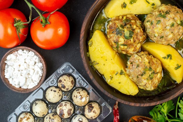 Nahaufnahme von leckeren Frikadellen-Eiern, grünen Salztomaten mit Stielen auf schwarzem Hintergrund