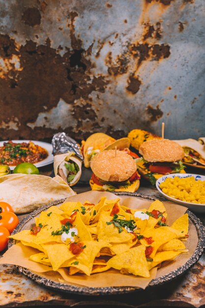 Nahaufnahme von leckeren mexikanischen Nachos; Burger; Mais; Tomaten- und mexikanische Rindfleisch-Tacos