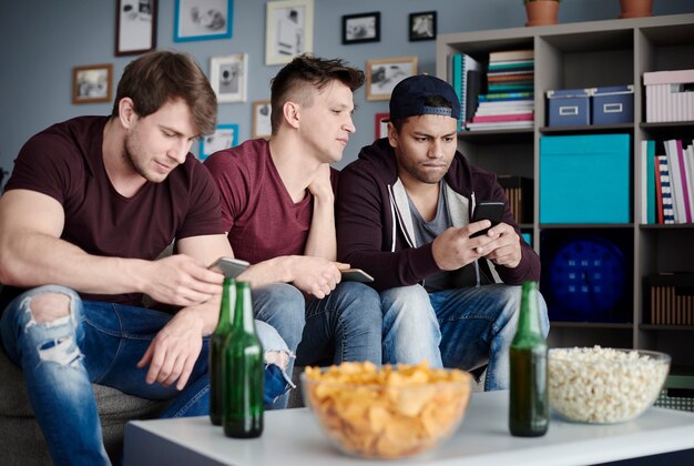 Nahaufnahme von Männern mit Smartphones im Wohnzimmer