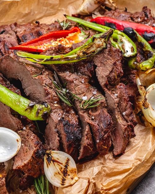 Nahaufnahme von mittel gekochtem Steak mit Knoblauchzwiebelrot und Chili-Pfeffer auf Pergamentpapier