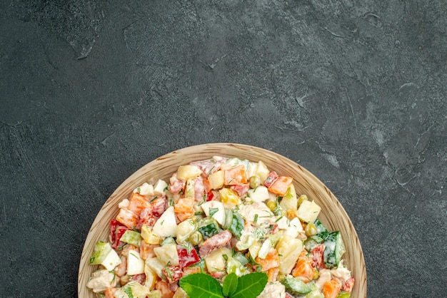 Nahaufnahme von oben auf die Schüssel mit Gemüsesalat auf der Unterseite mit Grün auf dunkelgrünem Hintergrund