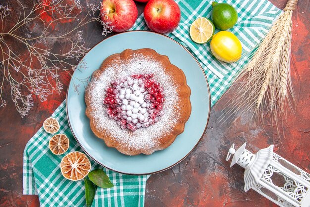 Nahaufnahme von oben ein Kuchen ein Kuchen mit Beeren Puderzucker Zitrusfrüchte auf der karierten Tischdecke