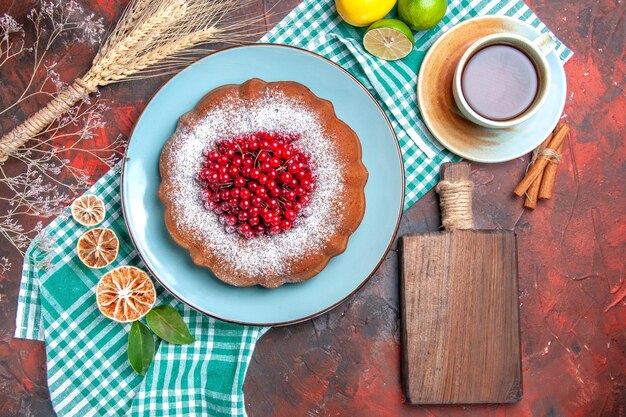 Nahaufnahme von oben ein Kuchen eine Tasse Tee Zimtkuchen Limetten auf der Tischdecke das Schneidebrett